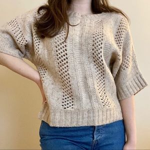 Short sleeved tan cable knit sweater.